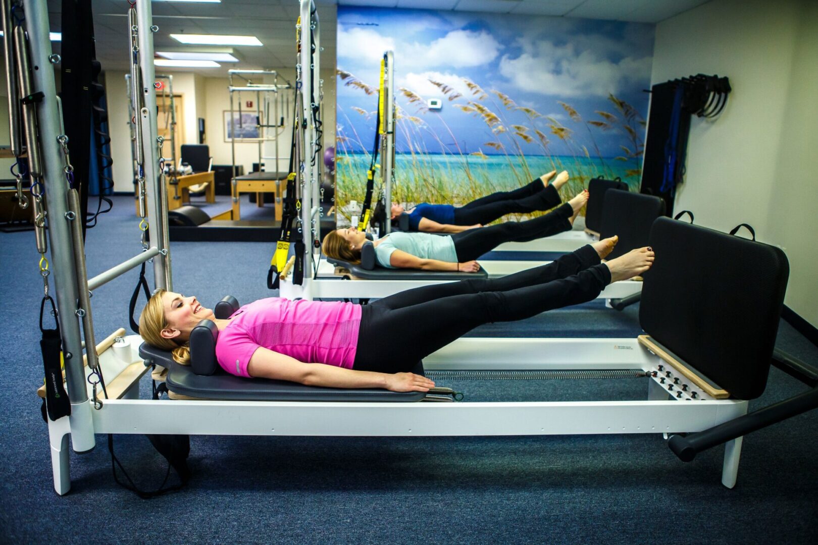 A woman is doing pilates on the reformer.