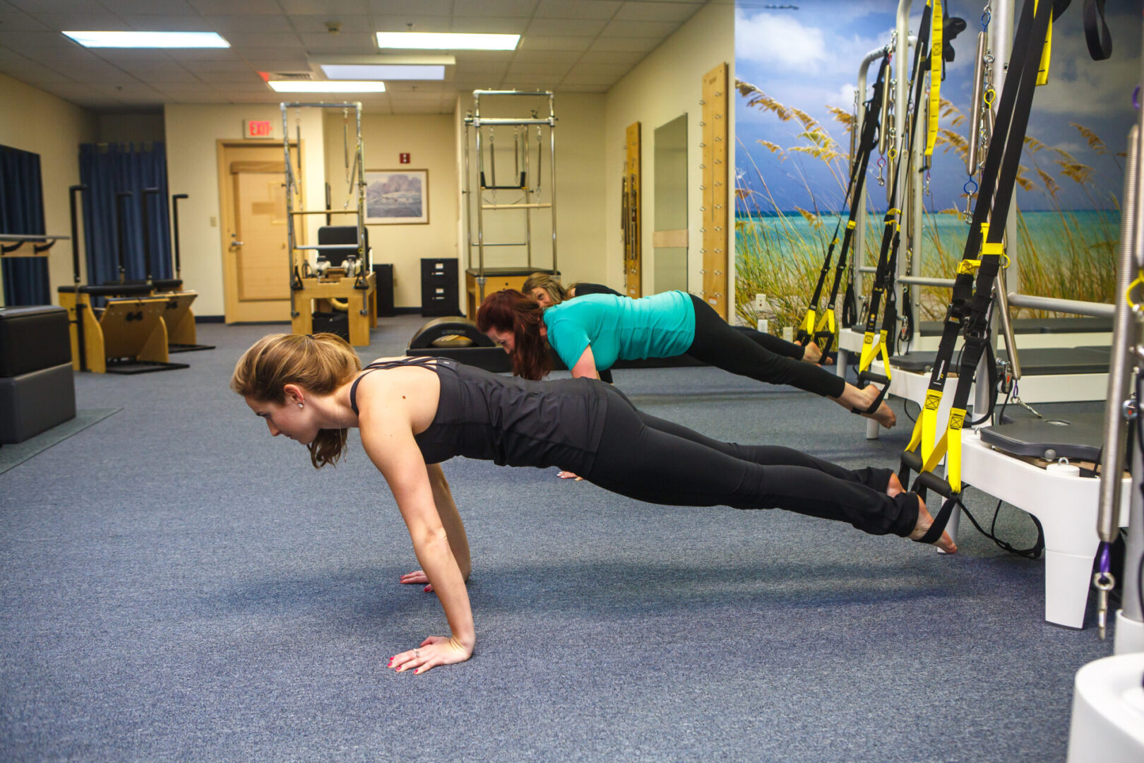 Two women are doing push ups on a trx.