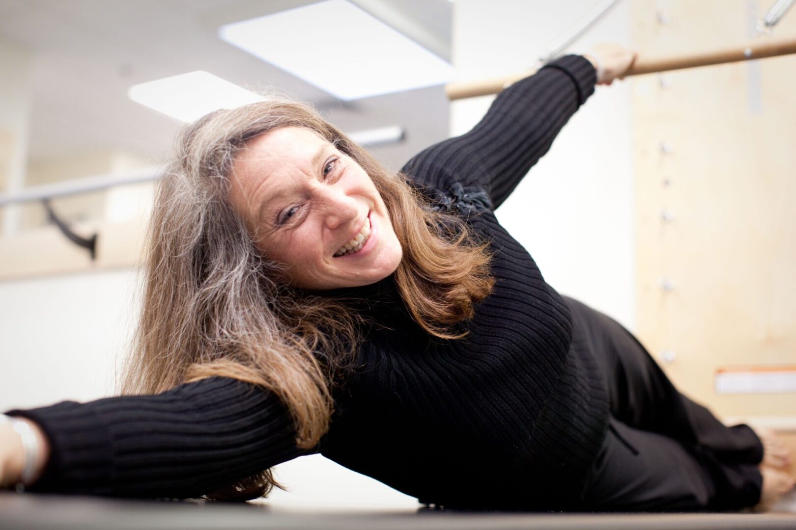 A woman is smiling while holding onto a pole.