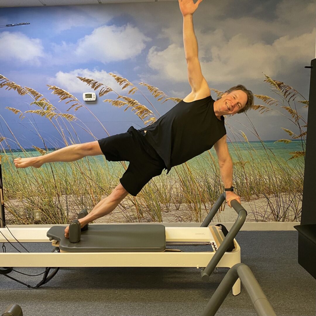 A man is doing a plank on the reformer.